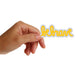 Hand holding a 'be brave' sticker by Matthew Hoffman with yellow text on a white background