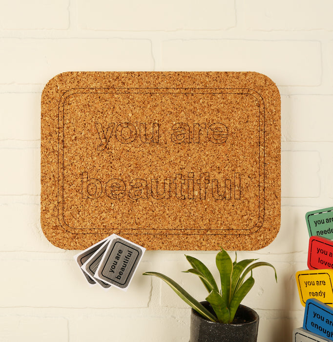 You Are Beautiful cork board holding daily calendar pages grid in home office setting