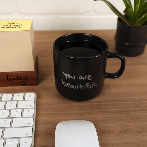 Matte black ceramic mug with “You Are Beautiful” handwritten in silver on one side, designed by Matthew Hoffman.